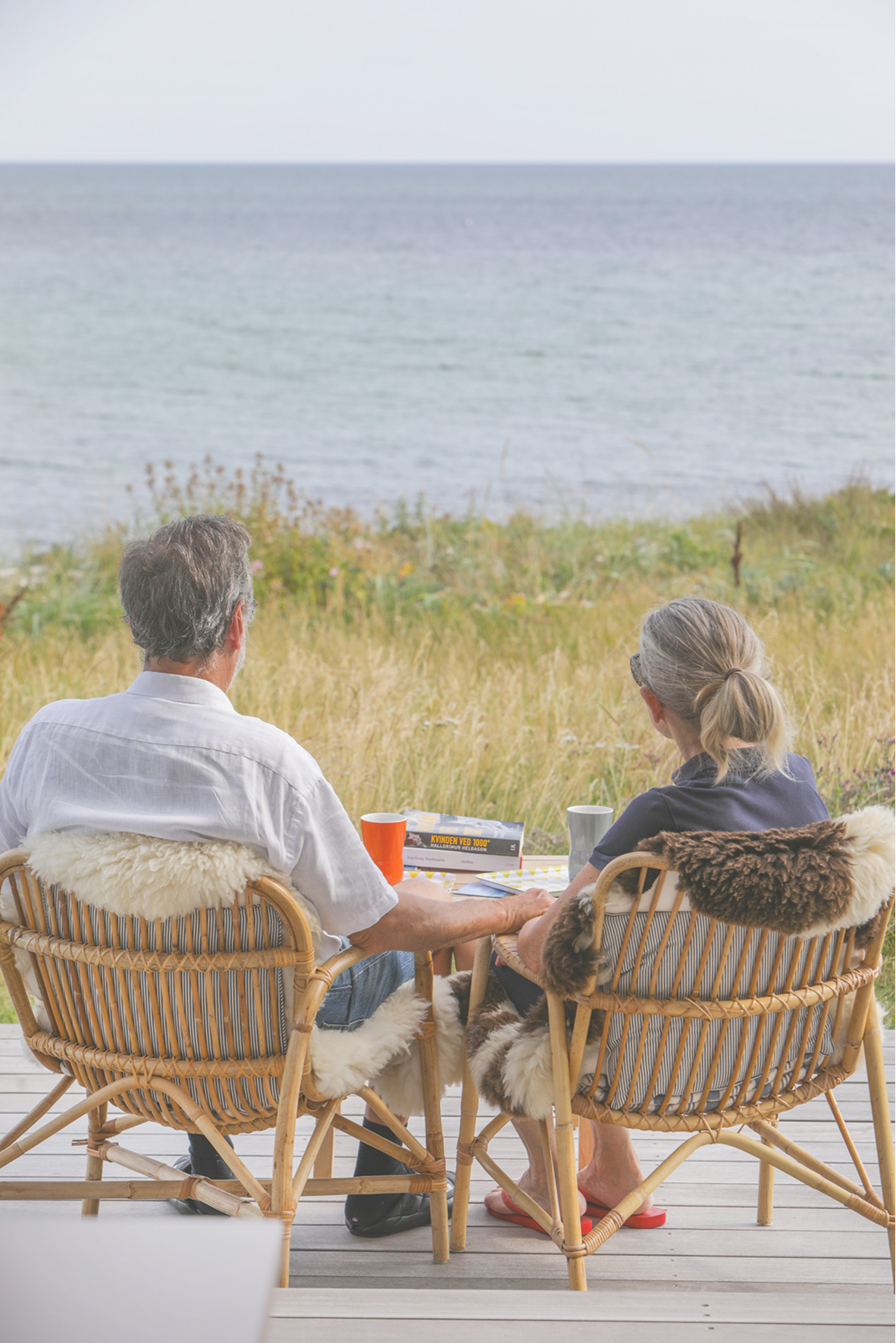 to voksne sidder på terrassen og nyder udsigten til vandet